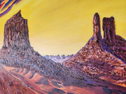 Close-up of the textured buttes in Clark Sheppard’s Monument Valley painting, highlighting thick palette-knife ridges, luminous yellows, and rugged rock formations rising from the desert landscape.brushstrokes that create a rugged desert floor with dimensional, glowing Southwest colors.