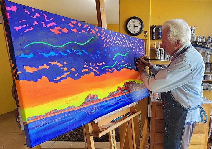 Clark Sheppard painting a fluorescent acrylic Southwest landscape on a large canvas in his Sedona Art Studios.